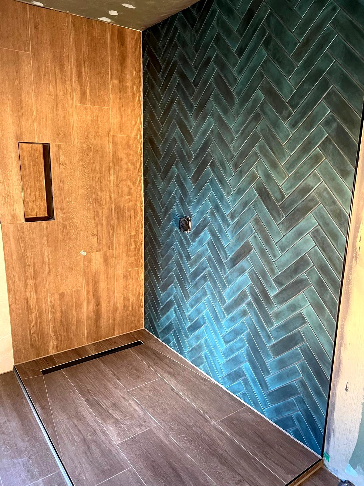 Bodengleiche Dusche mit türkisfarbenem Fischgrätmosaik und Boden in Holzoptik