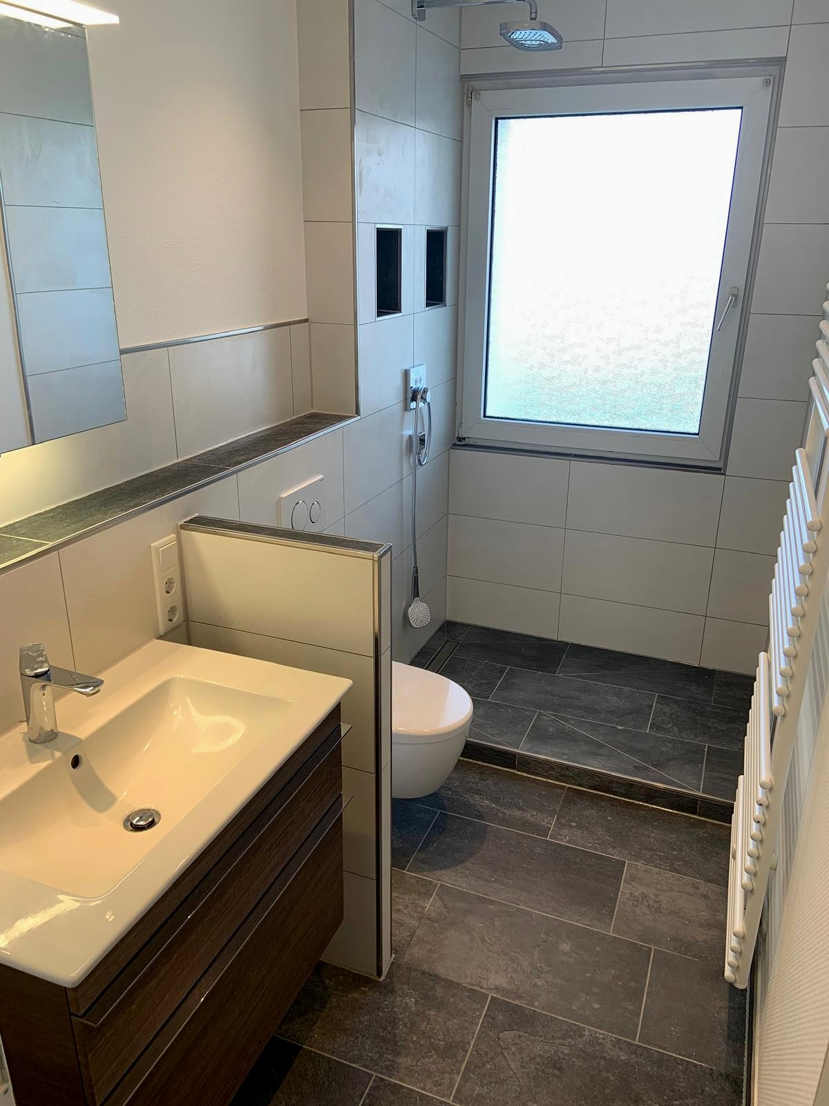 Kompaktes Bad mit wandhängendem Waschtisch, Wand-WC und dunklem Bodenbelag