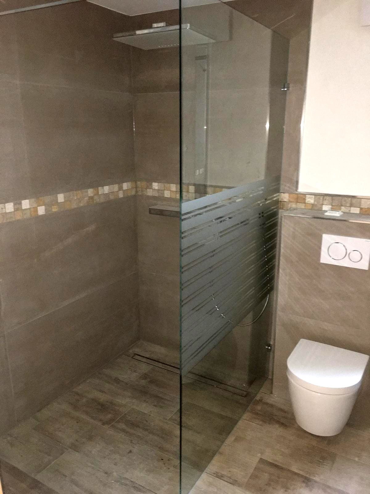 Bodengleiche Dusche mit Glaswand, umlaufendem Mosaikband und Boden in Holzoptik