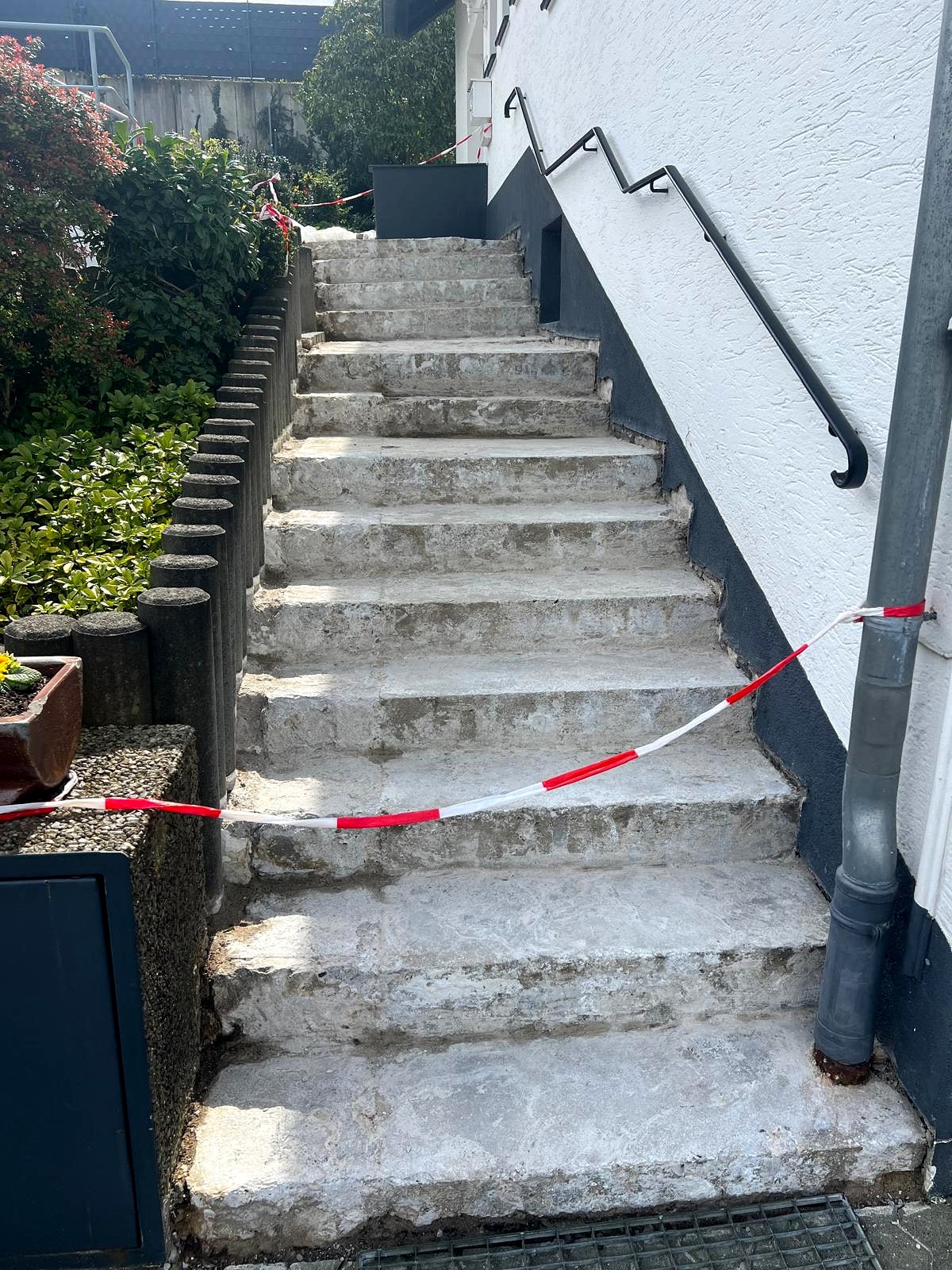 Außentreppe vor der Sanierung: abgestemmte, verwitterte Betonstufen, mit Absperrband gesichert