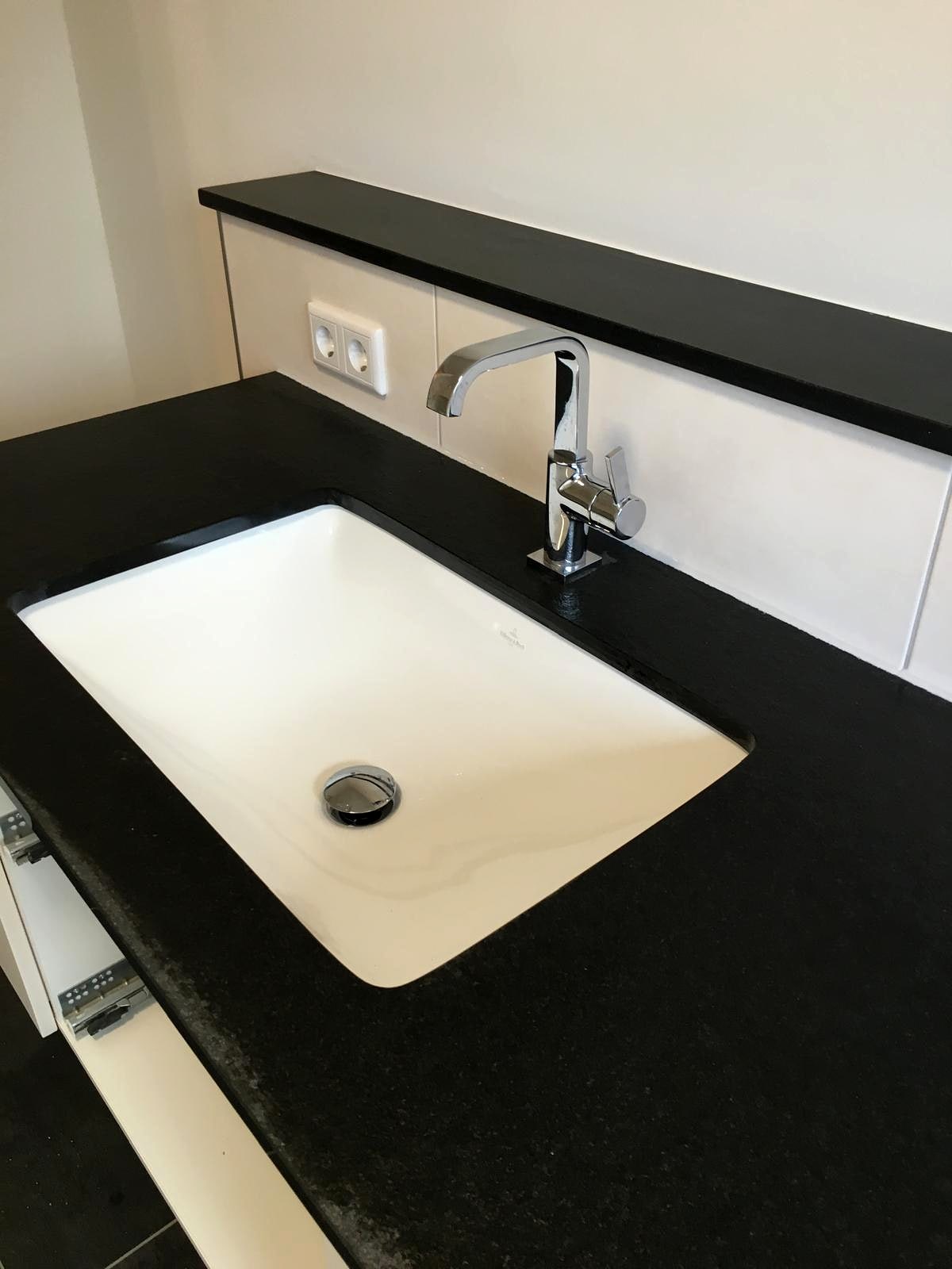 Waschtischplatte aus schwarzem Naturstein mit eingelassenem Unterbaubecken und Chromarmatur